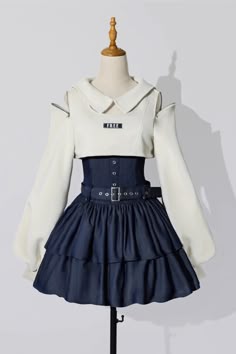 a white dress with long sleeves and a white collar. the dress is worn over a black corset and a blue ruffle skirt. the corset has a black belt with a silver buckle. the skirt is tiered and ruffles around the bottom. the dress is on a mannequin.