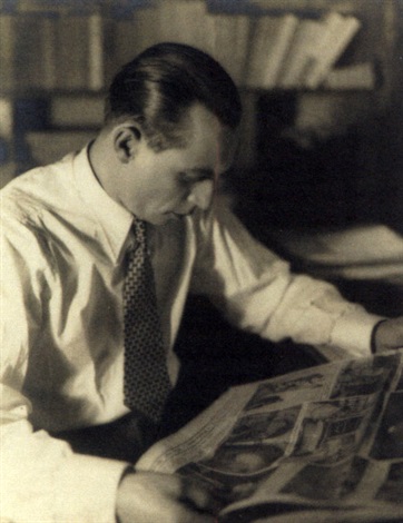 a black and white photograph shows a man seated indoors, deeply engrossed in reading a newspaper or magazine. he is wearing a lightcolored collared shirt and tie. the setting appears to be a study or library, with bookshelves visible in the background. the image has a vintage feel, suggestive of the 1920s or 1930s. the man's expression is serious and focused. the lighting is soft, highlighting his concentration on the reading material.