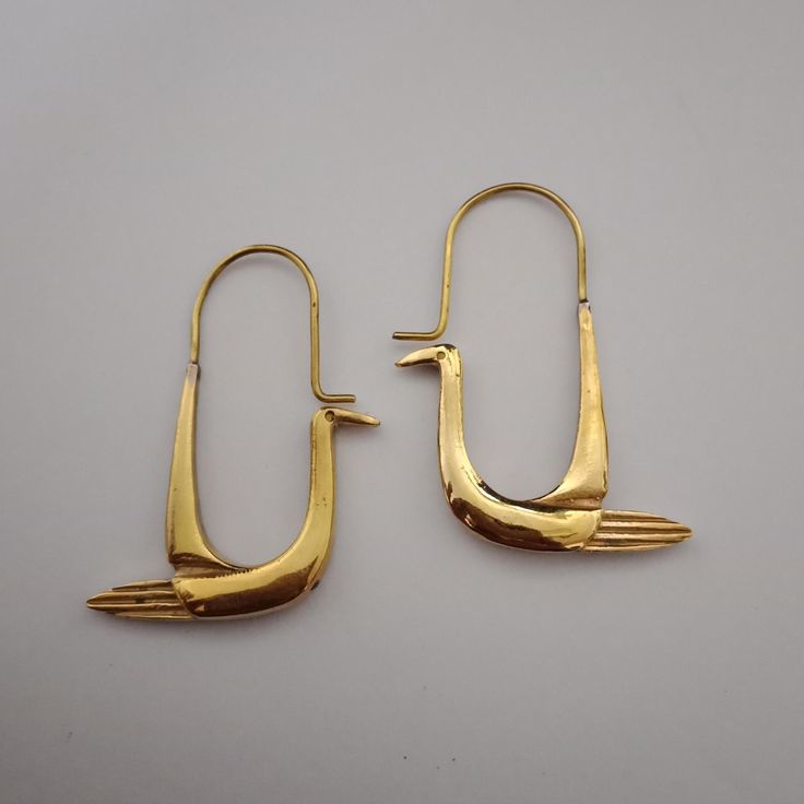the image shows a pair of gold earrings shaped like birds. they have a simple, stylized design with a hook for wearing.