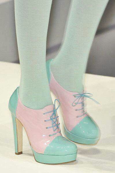 a close up of a woman's feet, wearing light blue and light pink  high heeled shoes with laces and an aqua blue and light pink skirt that are the same color as the shoes.  the shoes are stylish and  fashionable.