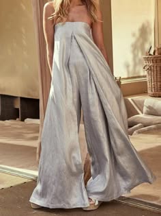 a woman stands in a stylish white linen jumpsuit, showcasing the relaxed and comfortable chic of the outfit. her elegant pose and the flowing fabric create a sense of effortless beauty. the image captures a moment of casual fashion, perfect for warm summer days.