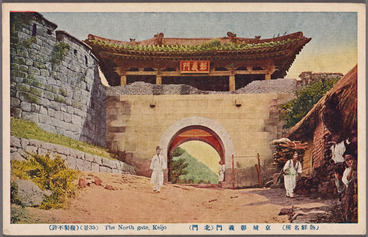 this is an image of the north gate in keijo. the architecture is of korean origin with a beautiful stone wall and an archway. a few people dressed in traditional clothing are captured in the image.
