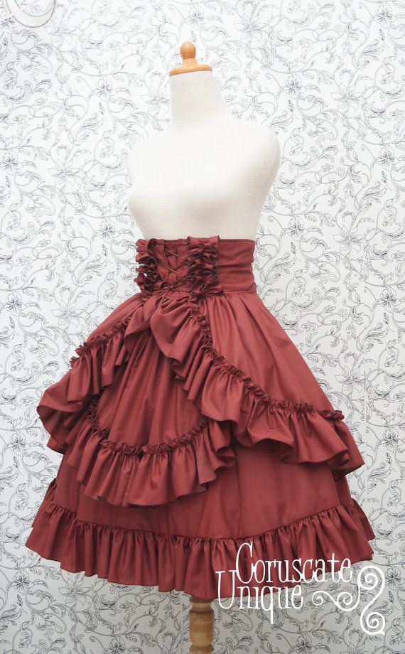 a maroon ruffled skirt is displayed on a mannequin. the skirt is highwaisted with ruffles at the waist. the skirt has several layers of ruffles. the background is a floral pattern.
