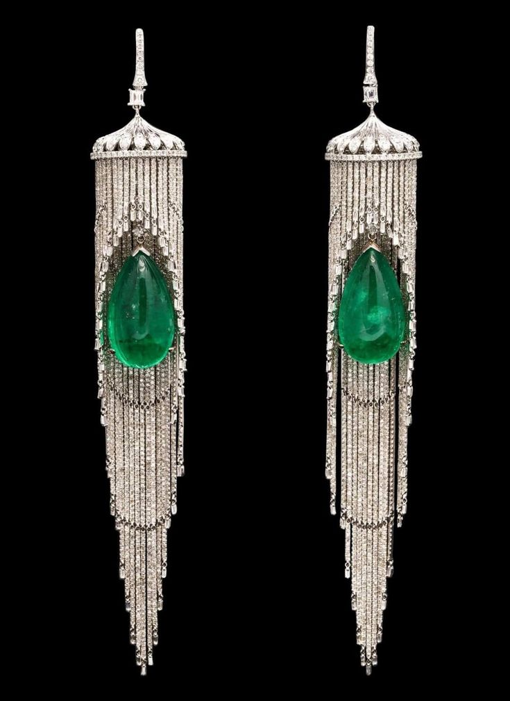 a pair of stunning emerald and diamond earrings with a vintage art deco design. the earrings feature a large, teardropshaped emerald set in a delicate cage of diamonds. the emerald is suspended from a series of graduated diamond chains, creating a dramatic cascade of sparkle. the earrings are both elegant and eyecatching, perfect for a special occasion.