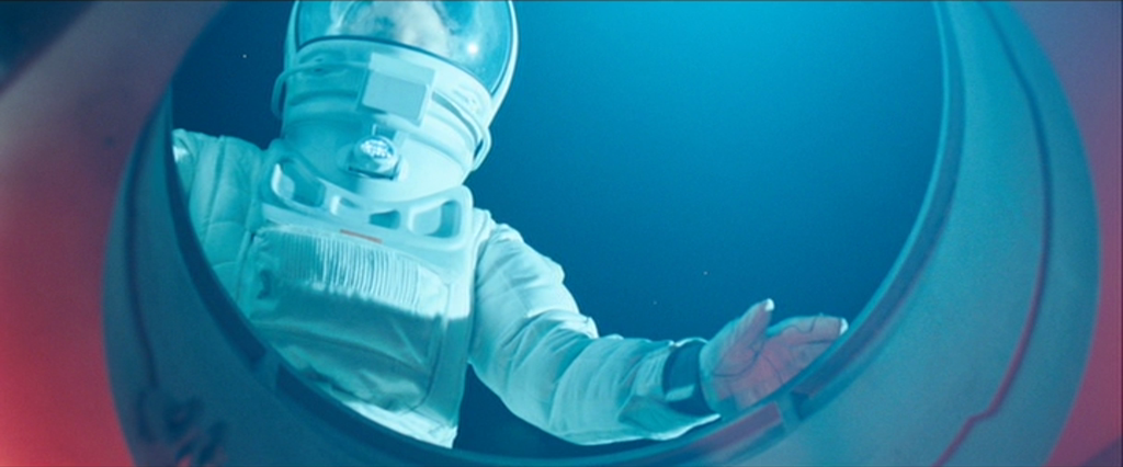 the image showcases an astronaut viewed from inside a spacecraft. they are peering out of a circular window, their hand gently touching the glass. the astronaut is clad in a white space suit, the only source of light seeming to emanate from within the spacecraft, casting an ethereal blue glow on the scene. the vast expanse of space, a deep indigo speckled with tiny stars, can be seen through the window.