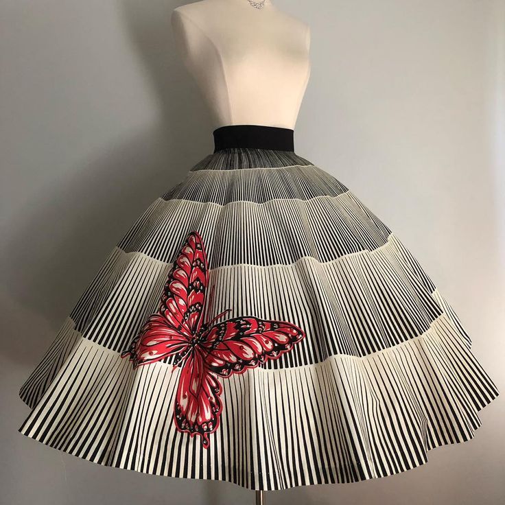 a skirt on a dress form. the skirt is black and white striped with a large red butterfly pattern on the front. the dress form is plain and white.