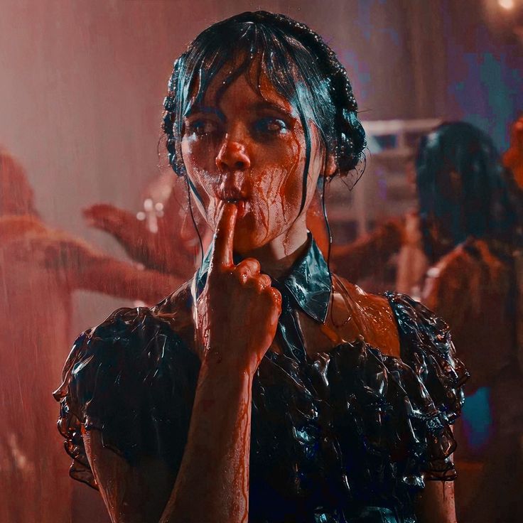 the image is a closeup shot of a young woman, seemingly covered in blood.  she's wearing a dark, ruffled gothicstyle dress and what looks like headphones are partially visible in her hair. her expression is ambiguous, with her finger to her mouth, possibly suggesting she's licking or tasting the blood. she's wet, as if from rain, and the overall atmosphere is dark and moody, evoking a horror or gothic film aesthetic.  the background is blurry but shows other figures that also appear bloody and wet, suggesting a chaotic or violent scene.  the color palette is dominated by dark reds and blacks, with the blood being a striking contrast against the dark dress. the image has a stylized, almost vintage or filmnoir look to it.