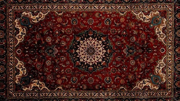 the image shows a detailed and ornate persianstyle rug or carpet. it features a predominantly red field with intricate floral patterns and motifs. a central medallion design dominates the center, surrounded by smaller floral elements. the rug is bordered with a decorative pattern of repeating shapes and floral accents, with larger, stylized floral corners in beige and blue. the color palette includes shades of red, beige, black, and hints of blue.