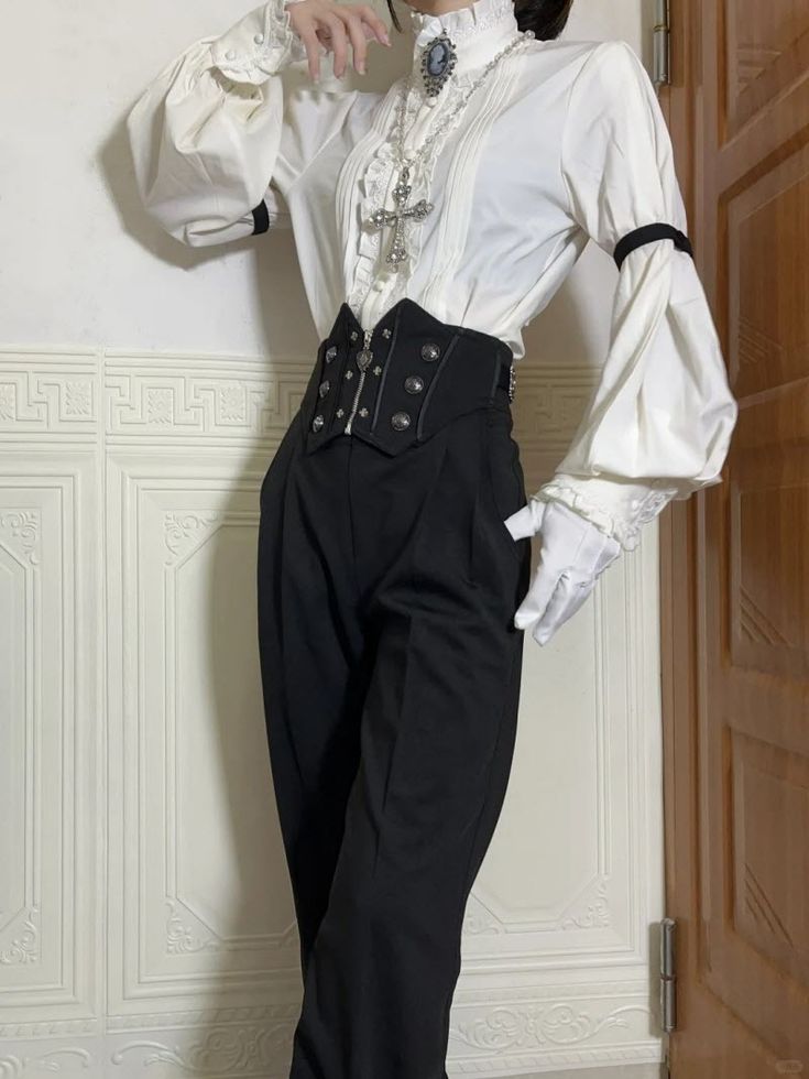 a person is wearing a white, victorianstyle blouse with ruffled detailing and puffy sleeves, paired with black wideleg pants cinched with a black corset belt. the ensemble is completed with white gloves and gothic jewelry, including a cross necklace and a cameo brooch. the person is standing in front of a wall and a partially visible door.