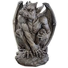 a stone gargoyle statue is shown crouching. it has large wings, a demonlike face with small horns, and is seated on a stone base. the statue appears aged and textured.