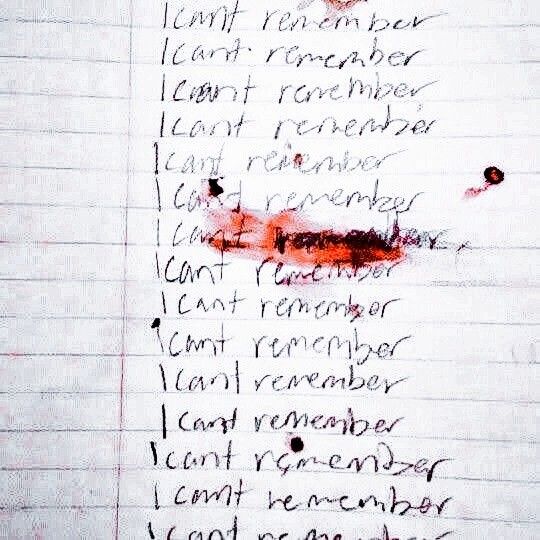 a piece of notebook paper with the phrase "i can't remember" written repeatedly down the page in black ink. some of the lines have splatters and smears of what appears to be blood on them.