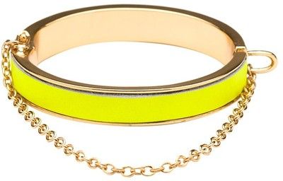 a closeup studio shot depicts a goldtoned bracelet featuring a prominent section of bright yellow. a gold chain hangs from the bottom edge of the bracelet.