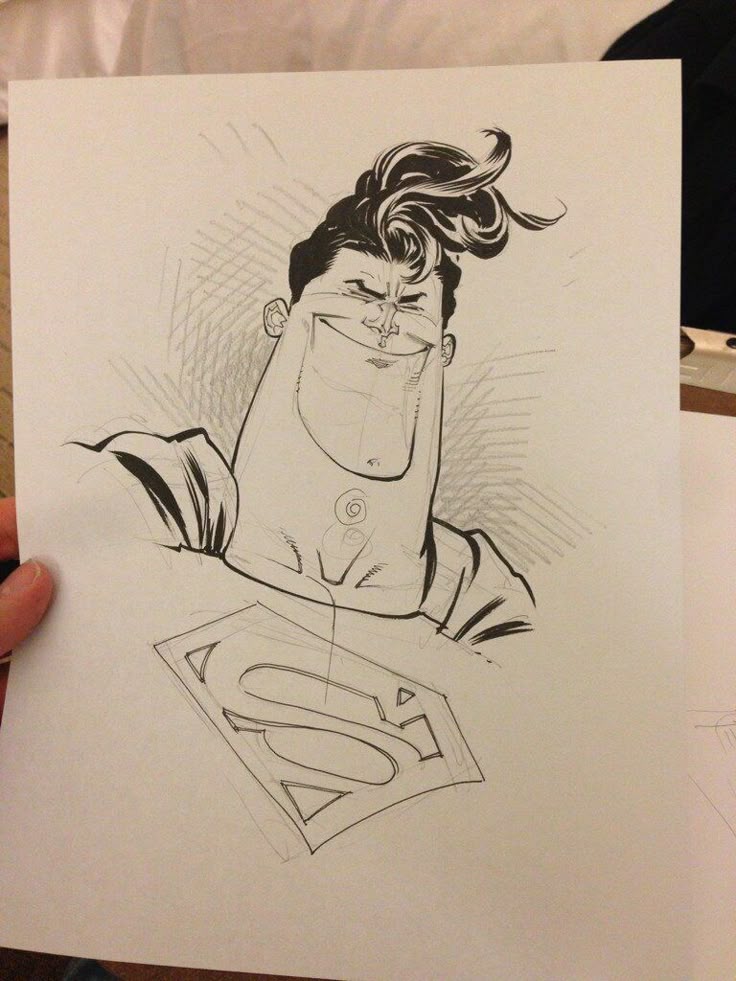 the image shows a humorous caricature of superman drawn in black and white on a sheet of paper. the drawing is a sketch with visible pencil lines and features exaggerated proportions, including a large jaw and a voluminous man bun hairstyle. superman's signature "s" logo is visible on his chest.