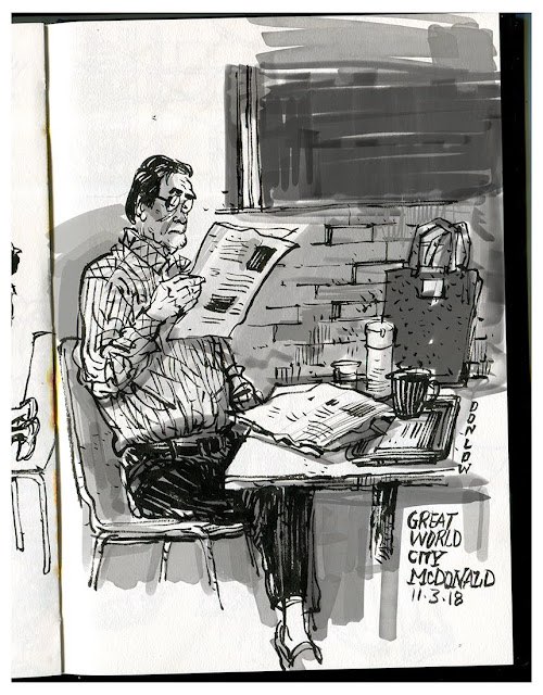 a black and white sketch of a man sitting at a table in a cafe reading a newspaper. the man is wearing glasses and a plaid shirt. there is a coffee cup and a bag on the table. the sketch is dated "11318" and has the words "great world city mcdonald" written on it.