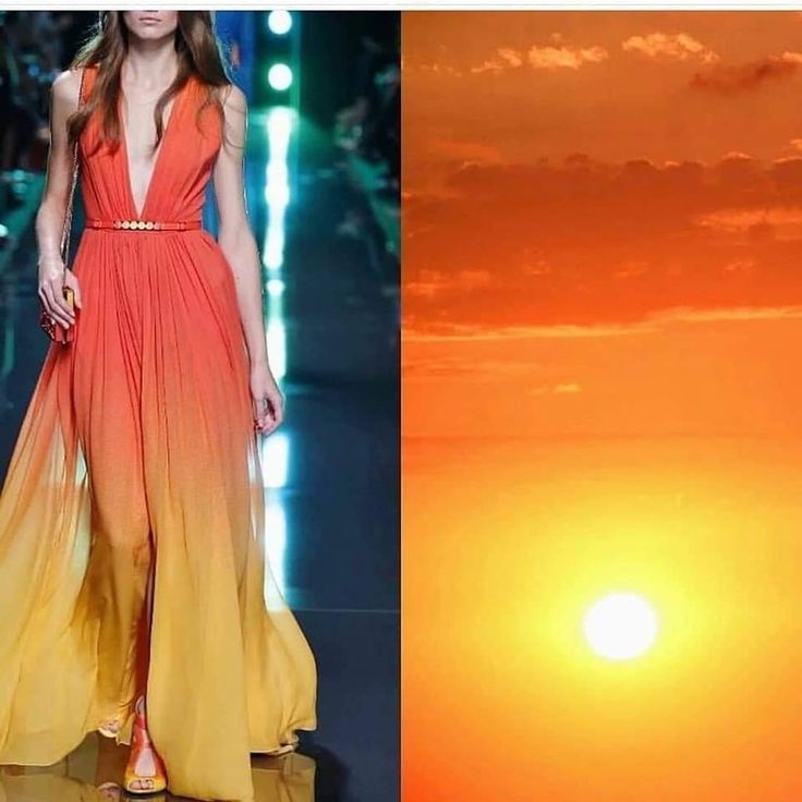 a woman in a beautiful orange to yellow gradient dress walks down a runway. the dress is very elegant and flows behind her. the background is a beautiful sunset with orange and yellow tones.