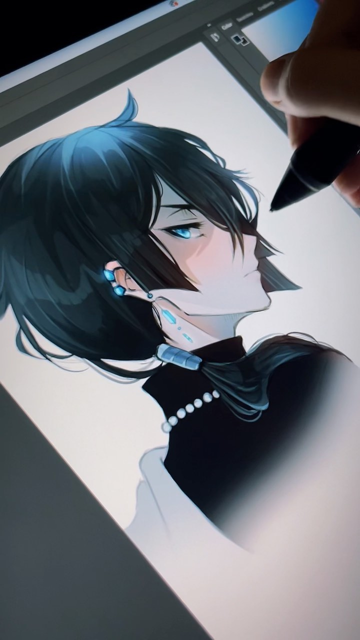 the image shows a closeup view of a digital artist's hand using a stylus on a graphic tablet.  the screen displays a work in progress: a detailed animestyle portrait of a young woman with long, dark blue hair, black clothing accented with a pearl necklace and blue earrings. the artist is focusing on the character's face and hair, adding shading and details. the overall style is elegant and realistic within the context of anime/manga art. the image highlights the digital art creation process.