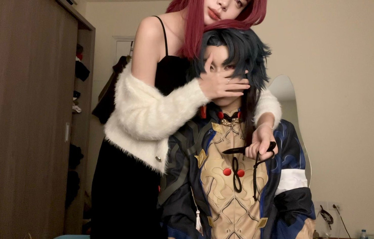 two friends are cosplaying. the girl is wearing a black dress with a white furry jacket, and the boy is wearing an intricate blue and gold animeinspired costume, with a white cuff and a black knife in hand. they are posing together with their hands on each other's shoulders, in a playful and friendly manner. they are standing in a brightly lit room. the background is a blur, but it is clear that they are indoors and are enjoying their time together. this photo captures the spirit of cosplay, fun, and the excitement of expressing oneself through costumes. it shows the joy and connection between the two friends, as they immerse themselves in their shared passion for anime and cosplay.