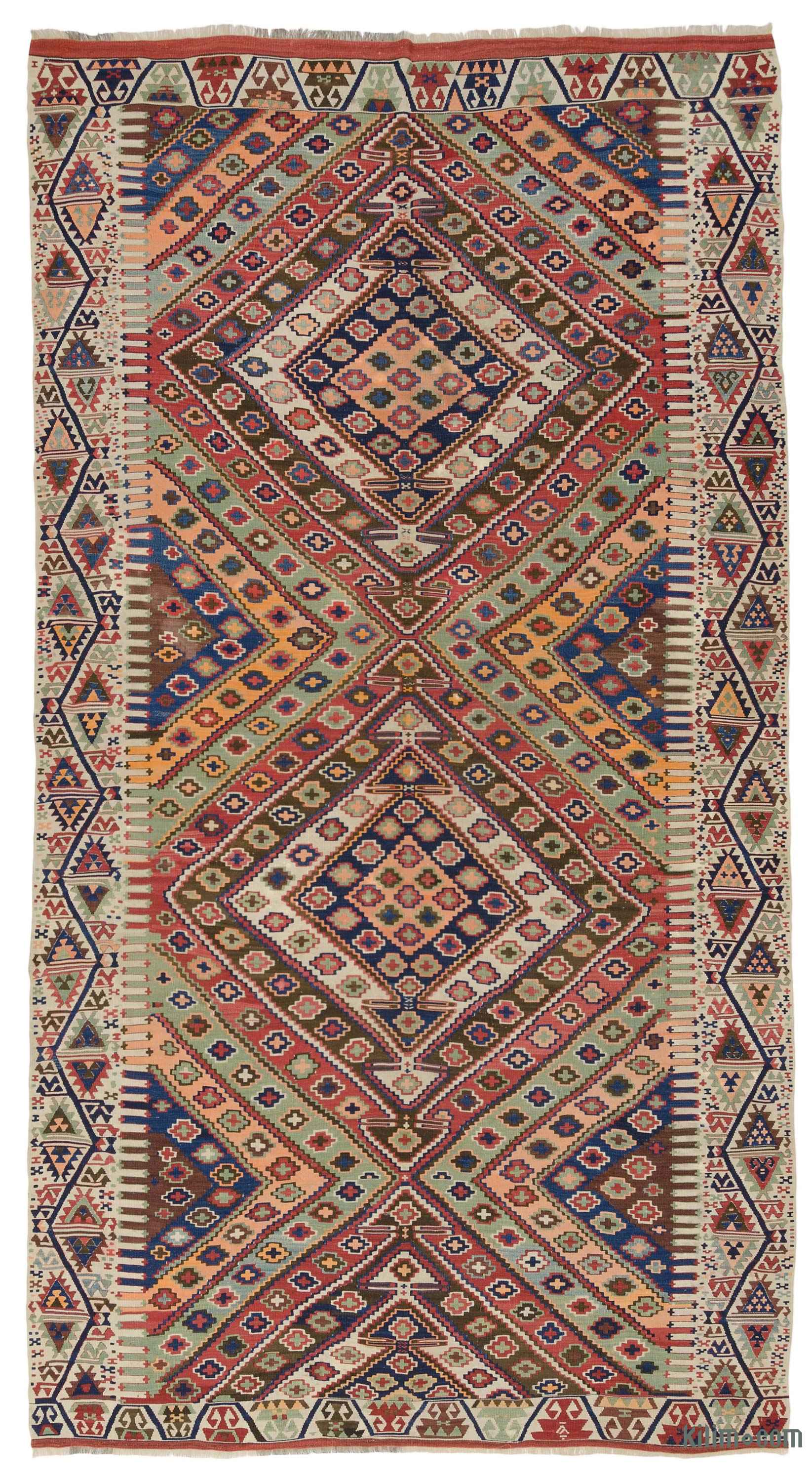 a brightly colored, patterned kilim rug with a central diamond motif. the rug features a variety of colors including red, blue, green, brown, and orange. the design incorporates geometric patterns, including diamonds and triangles, and has a border along the sides and top and bottom edges. the rug appears to be a traditional, woven textile.