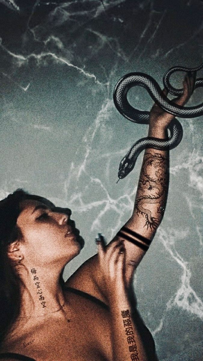 the image features a closeup portrait of a woman with various tattoos, including a prominent dragon tattoo on her arm and script tattoos on her neck and arm. a black snake wraps around her arm, adding a dramatic element to the scene.  the background is a dark, marbled texture, contributing to a moody and artistic atmosphere. the overall style is dark, aesthetic, and slightly gothic.  the woman's expression is serious and contemplative.