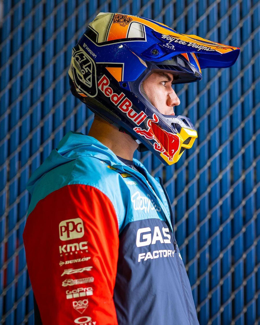 a person is wearing a red bull and gas factory motorcycle helmet and jacket. the helmet is a troy lee designs helmet.