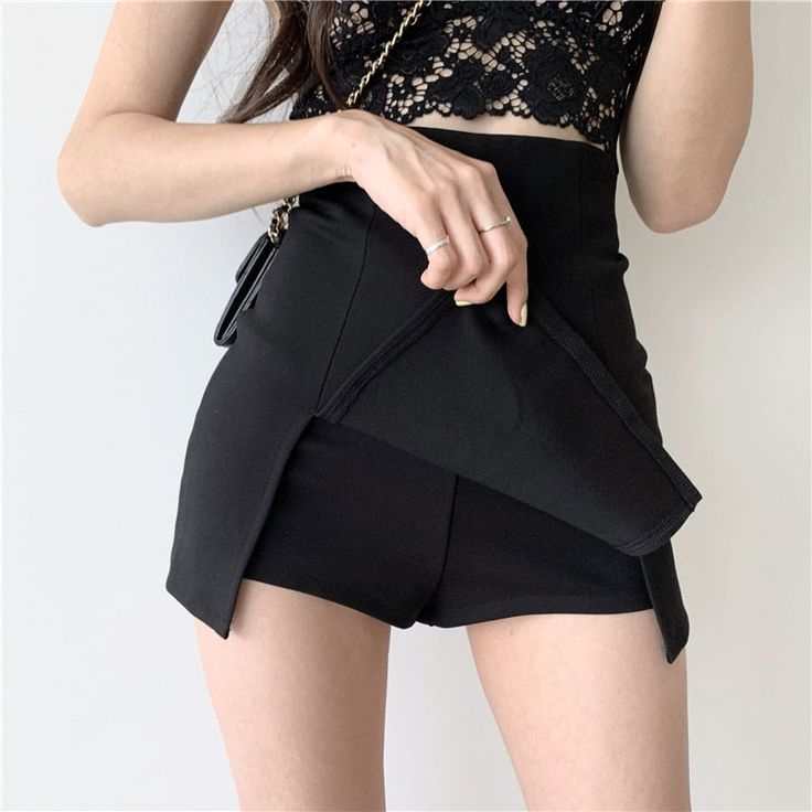 a young woman is wearing a black skirt and a lace top. she is standing against a white background. she is looking at the camera.