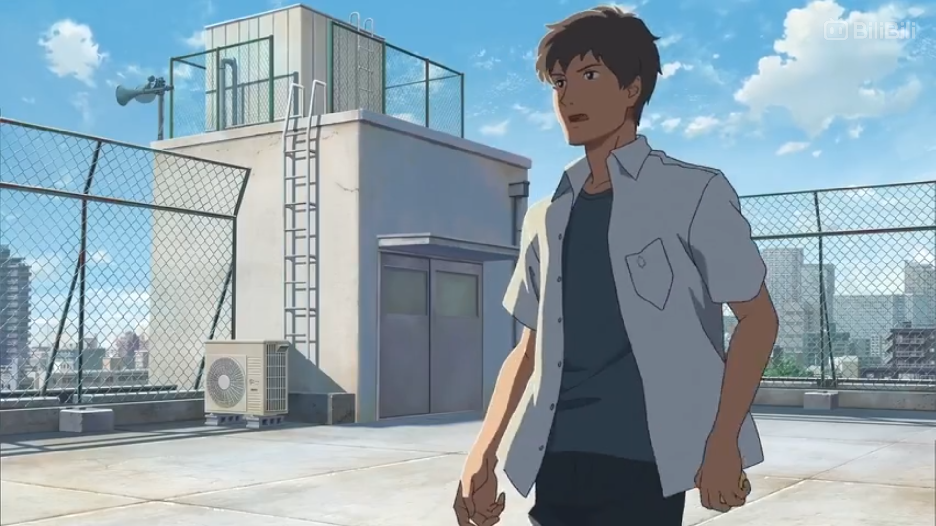 a young man with brown hair and a determined expression stands on a rooftop in an urban environment. he is wearing a light blue shortsleeved shirt and black pants. the rooftop is surrounded by a chainlink fence, and there is a small building with a water tank on it in the background. the sky is blue with a few white clouds.