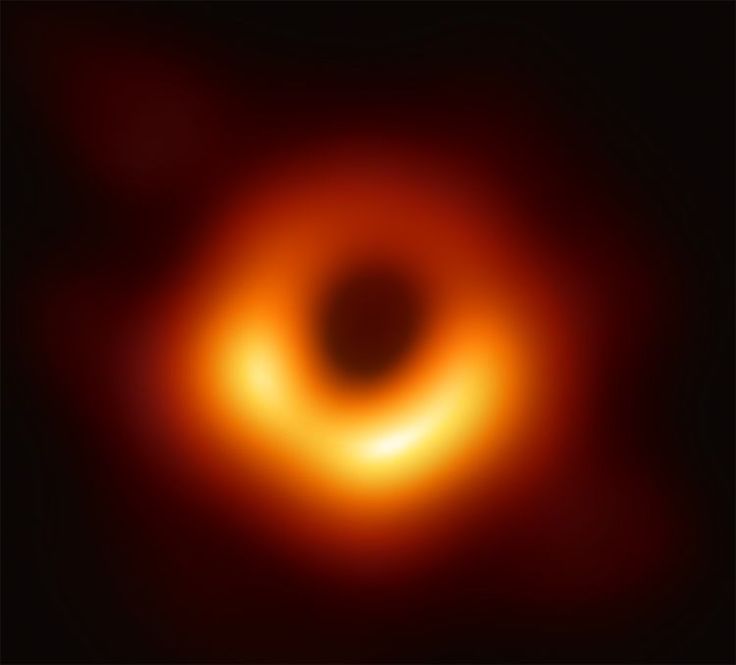 the image shows the firstever direct image of a black hole, specifically the supermassive black hole at the center of the m87 galaxy. the image depicts a bright ring of light, the accretion disk, surrounding a central dark area, which is the black hole's shadow. the ring's brightness is due to the superheated matter swirling around the black hole at relativistic speeds. the image is slightly blurry due to the immense distance and the limitations of the observing technology (event horizon telescope).  the overall color palette is dominated by shades of orange and red against a dark background.