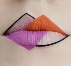 this image shows a closeup of a person's lips with a bold, colorful, and geometric design. the lips are outlined with a black liner and painted in three colors: pink, orange, and white. the design is arranged in a way that creates a sharp and geometric look. the image is a testament to the creativity and artistry that can be expressed through makeup.
