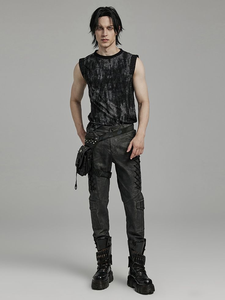 a fullbody studio shot of a male model wearing a dark grey sleeveless shirt with a distressed pattern. he's also wearing black cargo pants with a leg harness, a small shoulder bag, and chunky black studded boots.  the background is a simple, neutral grey. the style is dark, gothic, and alternative. the model is standing with a slightly posed stance.