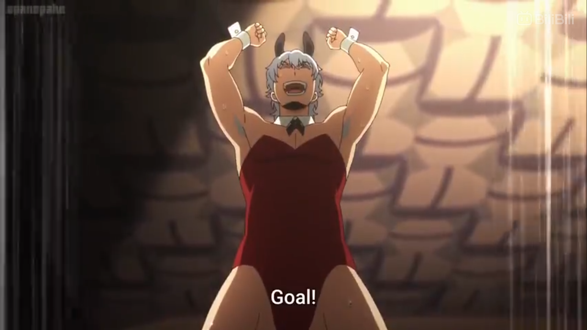 a young man with white hair wearing a red bunny suit raises his arms in celebration and says "goal!"  he is standing on a dark brown floor with a tan brick wall in the background.  there is a spotlight shining on him from above.