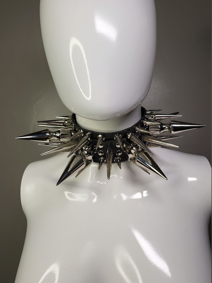 a closeup image of a silver spiked choker with a black leather base. the choker is displayed on a white mannequin's neck.