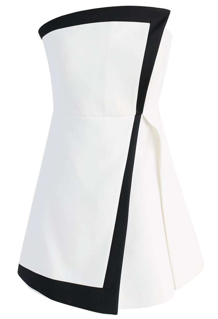a white strapless mini dress with black trim around the top and a diagonal strip down the front, as well as along the bottom hem. the dress has an overlapping panel on one side.