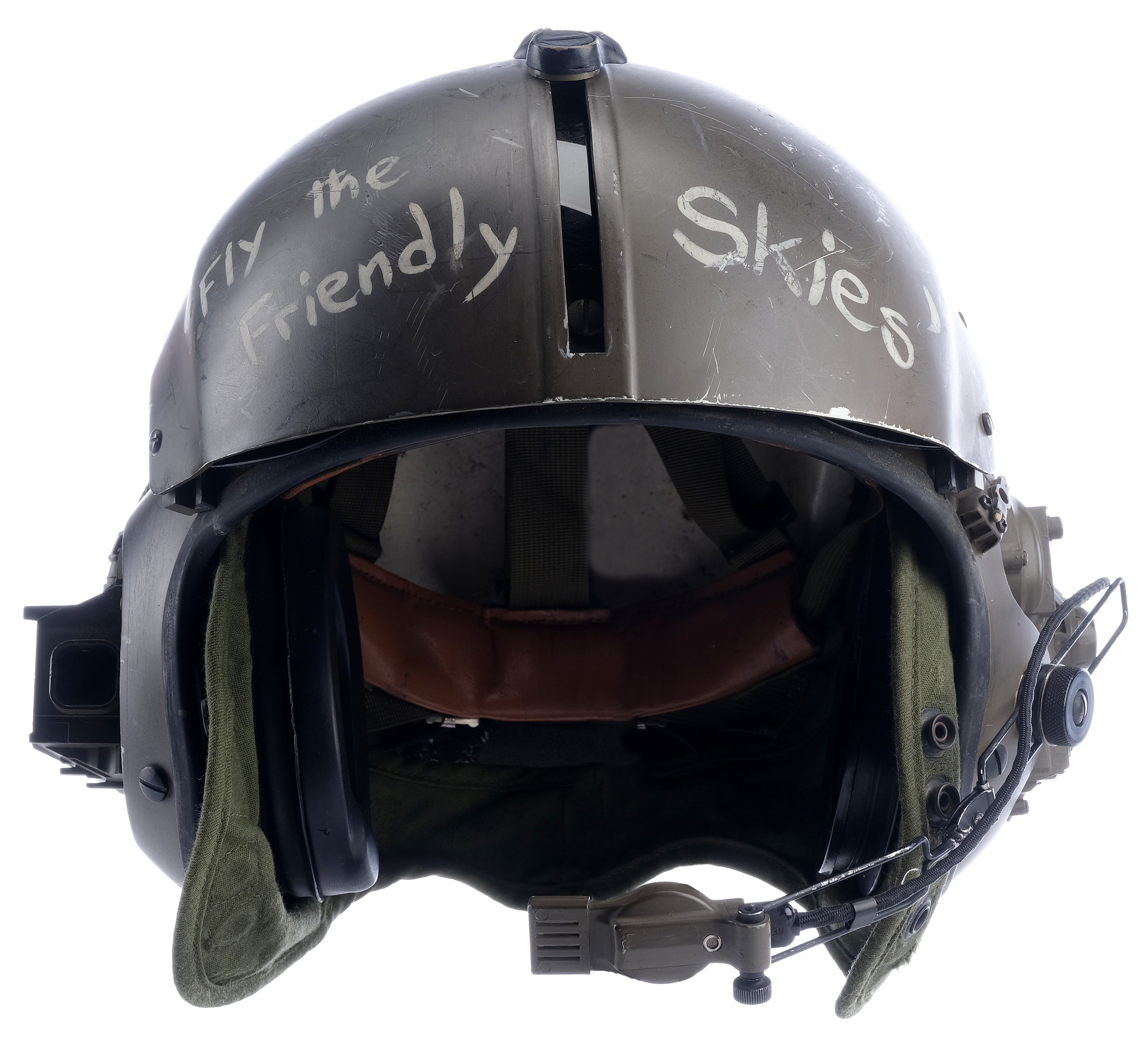 a black military helmet with the writing "fly the friendly skies" in white paint. the helmet is made of a dark green material and has a black visor.  the helmet also has a black microphone cord and a brown padded liner.  the helmet is isolated on a white background.