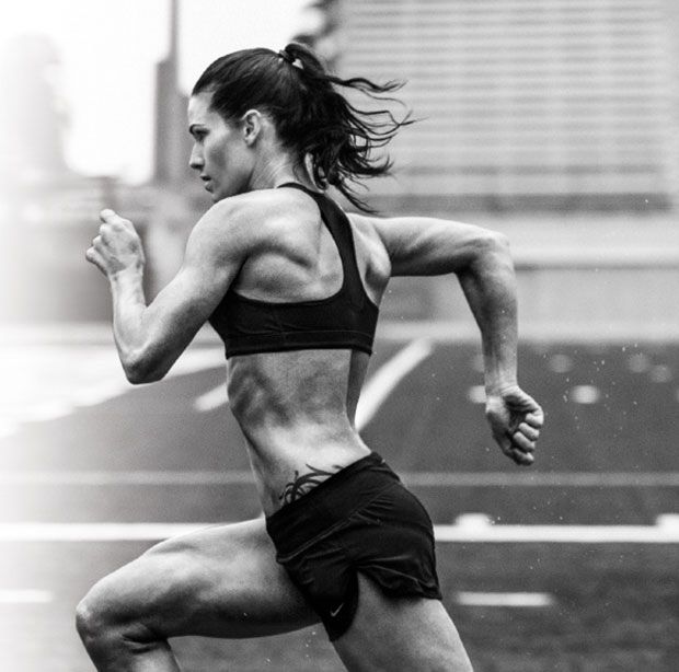 a black and white image of a female athlete running on a track. she is wearing a sports bra and shorts. she is focused on her training and is pushing herself to her limits. she is a powerful and inspiring woman who is dedicated to her sport.