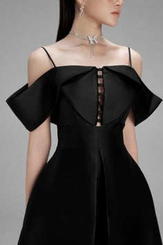 a woman wearing a black offtheshoulder dress with a butterfly choker. the dress is fitted and flows out in a skirt.
