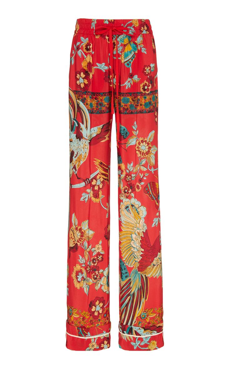 a pair of women's red wideleg pajama pants are shown. they are made of silk and have a vibrant floral print with birds. the pants have an elastic waistband and drawstring.  the bottom of the pants have a contrasting trim. the overall style is elegant and comfortable.