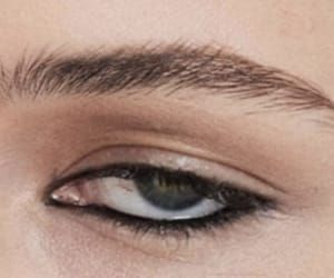 closeup photo of a woman's eye with a natural, defined eyebrow and eyeliner. the photo is in focus, highlighting the intricate detail of the eye and the subtle makeup application.