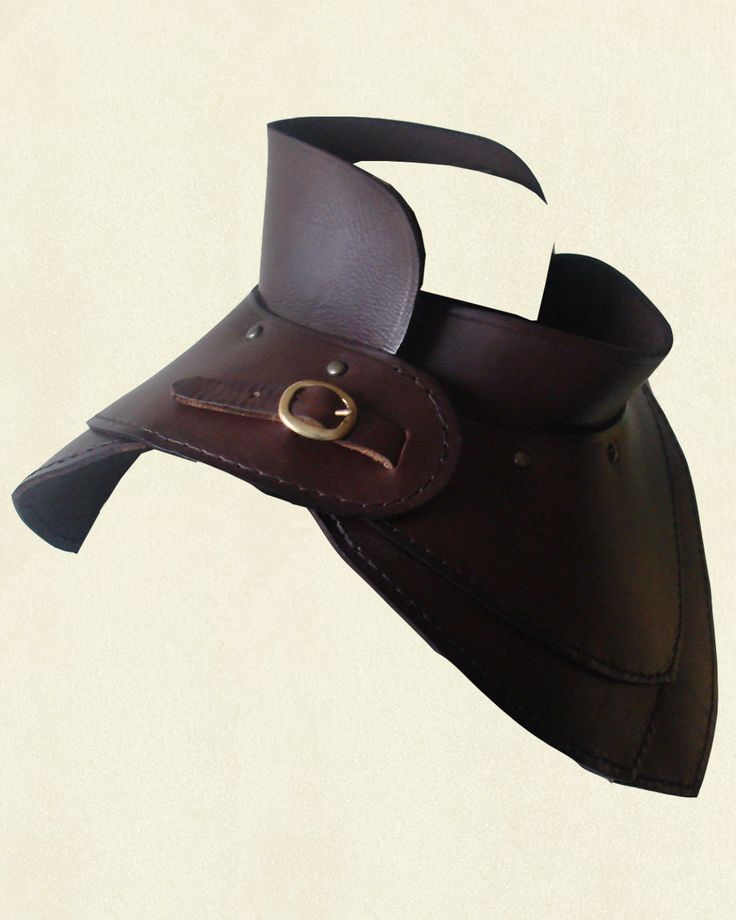 a brown leather collar, possibly for a costume, sits against a beige background.  the collar is a medieval or renaissance style. the leather appears to be thick and is held together with a buckle and rivets.  the collar appears to be worn around the neck.