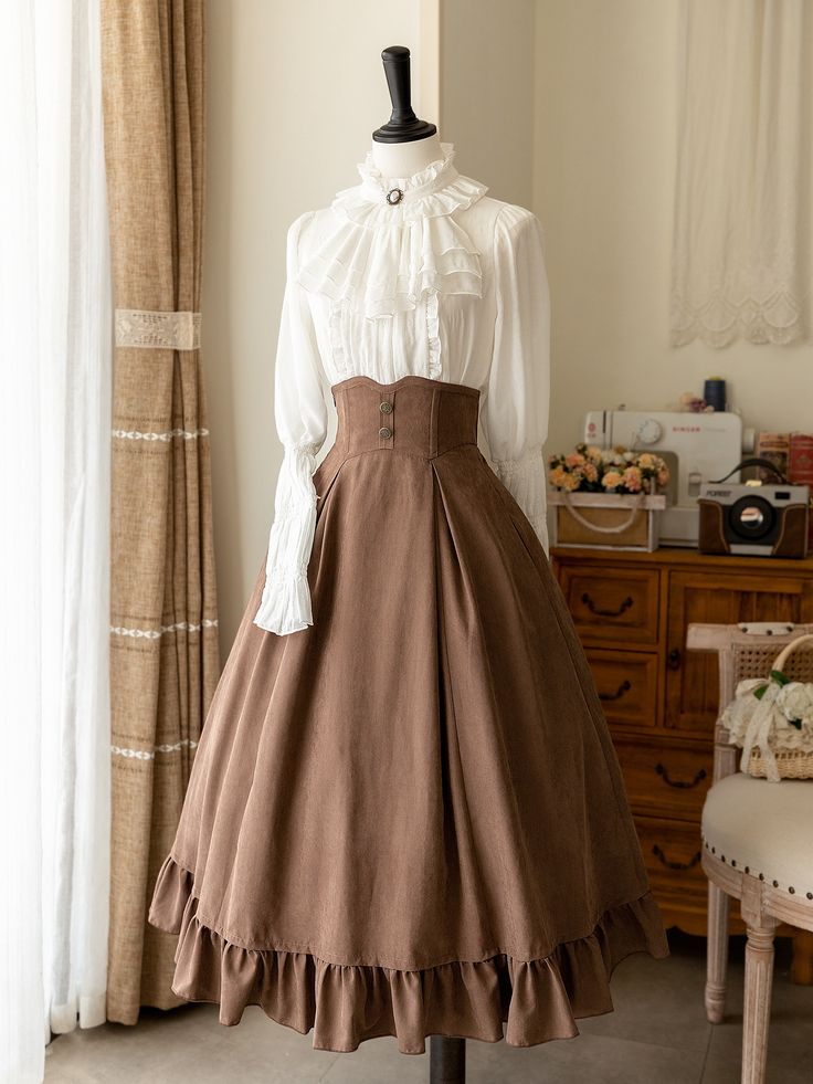 a brown victorianstyle skirt and white ruffled blouse are displayed on a mannequin in a brightly lit room. the skirt is highwaisted with a ruffled hem, and the blouse has a high neck and long sleeves. the background includes a curtained window, a wooden cabinet, and a white chair with a floral cushion.