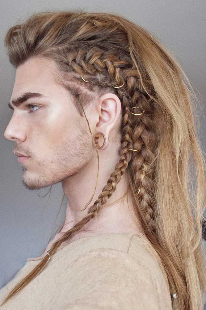 a man with long blonde hair styled in a vikinginspired braid is shown in profile. a french braid runs along the side of his head and down his back, adorned with gold rings. he has an ear piercing.