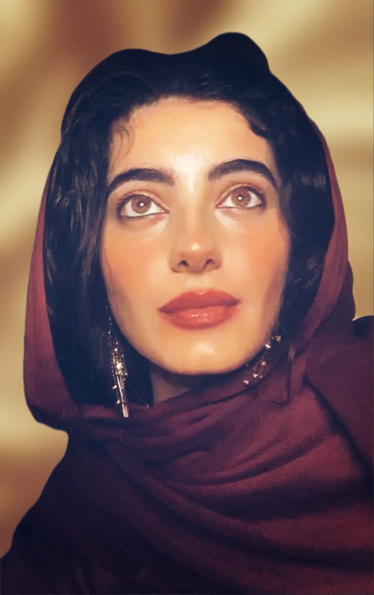 a closeup portrait of a woman wearing a maroon headscarf. she has fair skin, dark hair, and brown eyes that are looking upward. she has red lipstick and is wearing long, dangling earrings. the background is a soft, blurred gold tone.