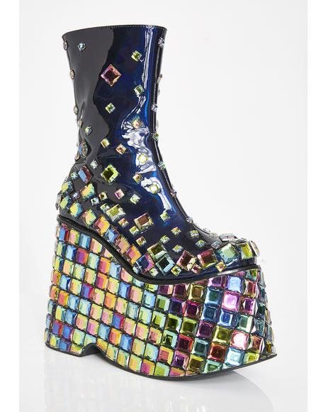 a single, highfashion platform boot is displayed against a plain white background. the boot has a glossy, dark blue shaft adorned with iridescent square crystals. its platform sole is also covered with the same iridescent squares, arranged in a colorful, gridlike pattern. the lighting highlights the reflective surfaces of the crystals and the glossy boot shaft.