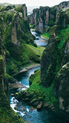 a beautiful view of a river flowing through a green canyon. the river is turquoise blue and the canyon walls are covered in moss and green vegetation. the cliffs are tall and steep, and the river appears to be flowing through a narrow passage. the scene is serene and peaceful.