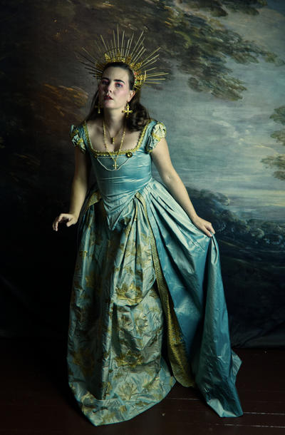 a fulllength portrait of a woman in an elaborate teal and gold 18thcentury style gown. she is wearing a golden crown or tiara and several pieces of jewelry, including a necklace with a cross pendant and earrings. the background is a dark, moody painting with a seascape. the woman's pose and expression are regal and mysterious. the overall mood is dramatic and evocative of historical portraiture.  the image has a high level of artistic styling and detail.