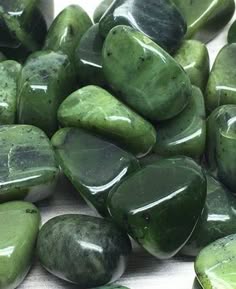 a closeup image of a collection of smooth, polished green jade stones. the stones are arranged in a random pattern, with some overlapping. the green color of the stones is varied and rich, and the smooth texture makes them feel soft and inviting. the stones are a beautiful example of nature's artistry.