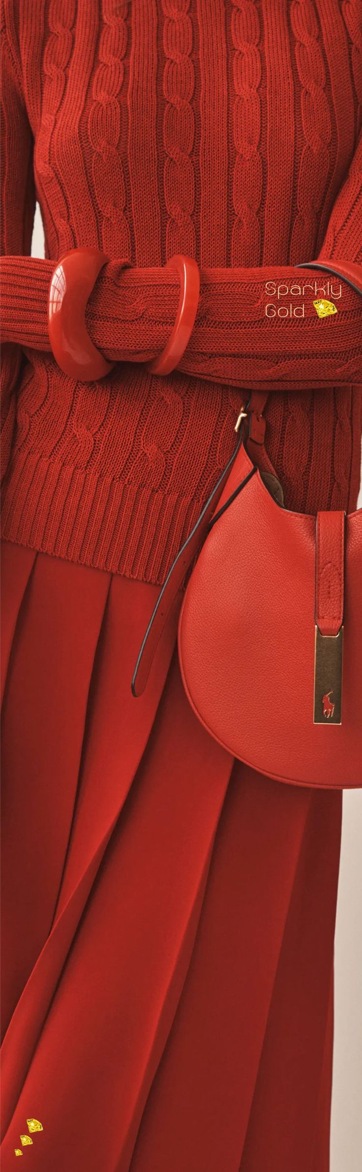 the image shows a closeup of a woman wearing an allred outfit.  the outfit consists of a red cableknit sweater and a matching pleated midi skirt.  she's also carrying a small, round red leather handbag with a subtle logo detail. the overall look is monochromatic and elegant, conveying a sense of sophisticated style. the focus is on the textures of the knitwear and the leather, and the way the red tones are coordinated.