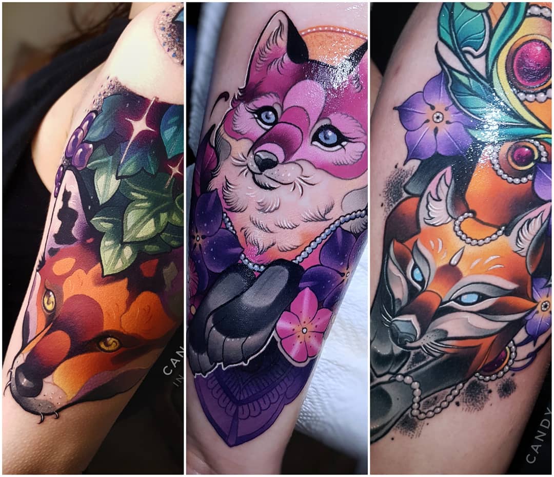 the image is a threepart collage showcasing a vibrant neotraditional tattoo of two foxes. the left panel shows the head and shoulders of a realistic orange fox with piercing yellow eyes. the middle panel features a pink and white fox with striking blue eyes, adorned with pink flowers and a purple jeweled collar. the right panel displays the head of the orange fox from a slightly different angle, embellished with pearls and positioned beside a peacock feather and purple flowers. the tattoos are rendered with bold lines, rich colors, and intricate details.
