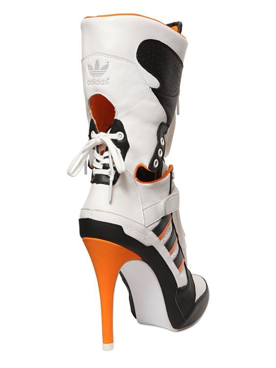 a pair of white and black adidas hightop sneakers with orange accents and high heels. the shoes have laces and are made of leather. the shoes are for women.