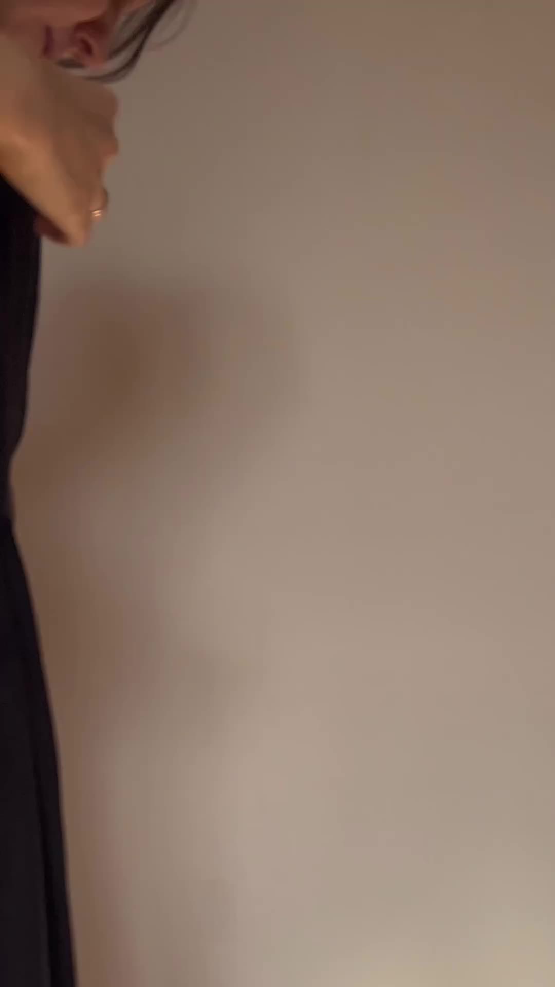 a closeup image shows a woman wearing a black dress and a ring on her finger. the camera focuses on her face and hand.