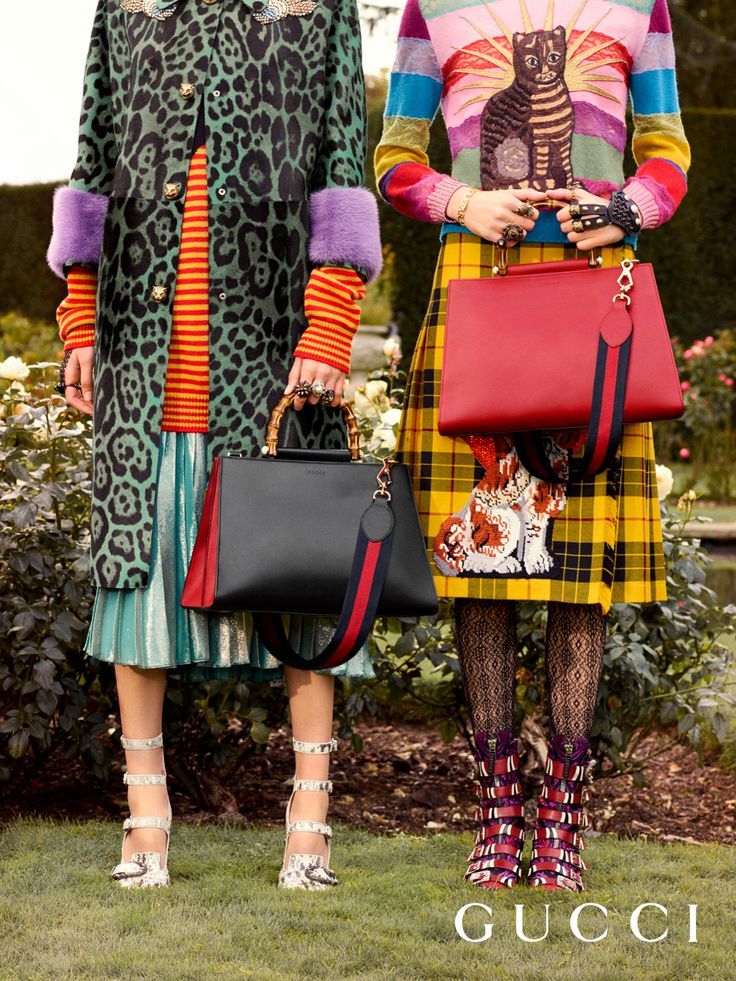 the image showcases two female models, each dressed in distinct yet stylish gucci outfits.  the model on the left wears a green leopardprint coat over a striped top and metallic pleated skirt, accessorized with a black gucci handbag and snakeskin heeled shoes. the model on the right is wearing a vibrant multicolored sweater with a cat graphic, a yellow and black plaid kilt, and striking patterned boots;  she carries a red gucci handbag.  both are positioned outdoors in a garden setting, demonstrating the complete gucci look. the gucci logo is prominently displayed at the bottom of the image.